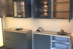 German Kitchen light grey wall storage with grey shelves and LED lights inside 