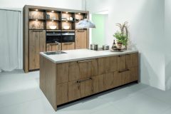 Wooden pastel smoke German kitchen with white topped surface and sink 