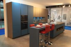 Dark wooden German kitchen cupboards with blue doors and red bar stools